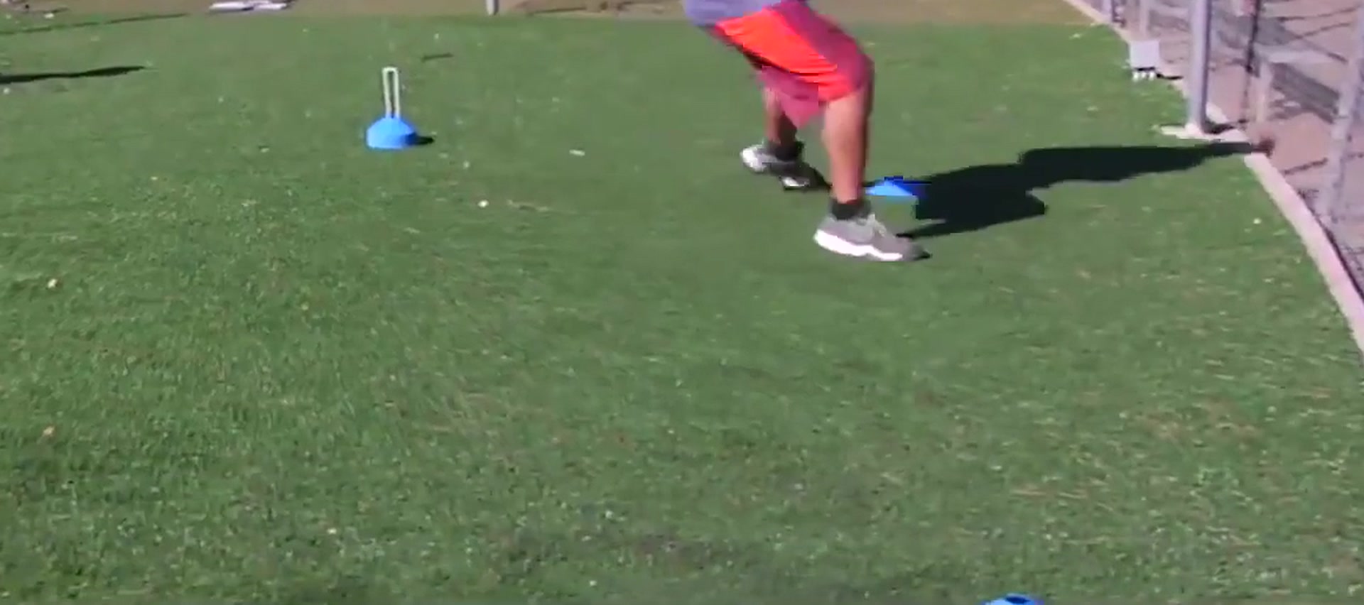 A player's legs and feet mid-stride on an agility drill, cones on the turf